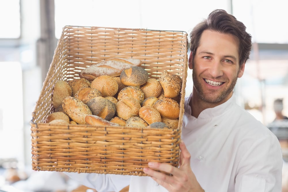 Baker showing basket of bread in the kitchen of the bakery